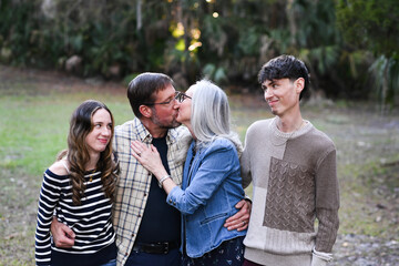 Obraz premium Couple kissing while their children react with amused expression