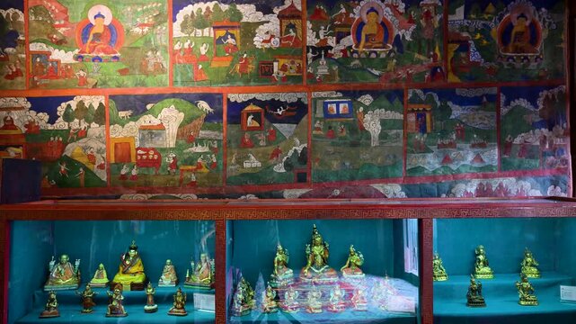 Ancient Buddhist art inside Erdene Zuu Monastery, Mongolia: vibrant historic wall murals and a collection of small gilded deities in a glass display showcase traditional religious craftsmanship.