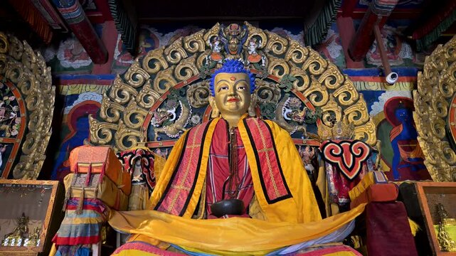 Close-up of a gilded Buddha statue face at Erdene Zuu Monastery, Mongolia. The historic deity features intricate gold details and vibrant blue hair, showcasing ancient religious artistry.