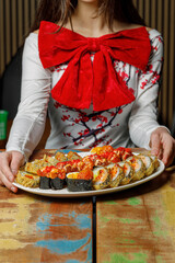 Girl with a big red bow holding a sushi set for a holiday