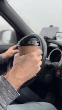 Man holding coffee cup while driving a car, showcasing daily commute lifestyle concept