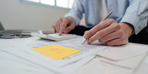 Tax Preparation. Individual calculating taxes with documents and calculator at home office.