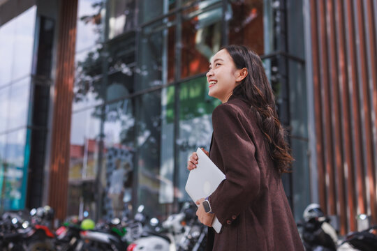 Young asian woman smiling walking with laptop working