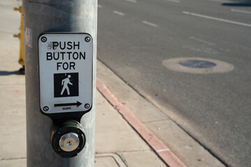 Push button for pedestrian crossing on a metal pole next to a street
