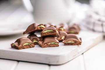Chocolate bar with pistachios cream on white table.