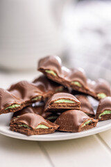 Chocolate bar with pistachios cream on plate on white table.
