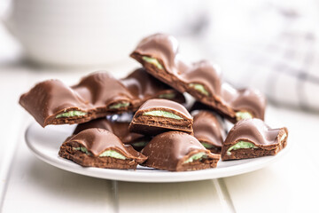 Chocolate bar with pistachios cream on plate on white table.