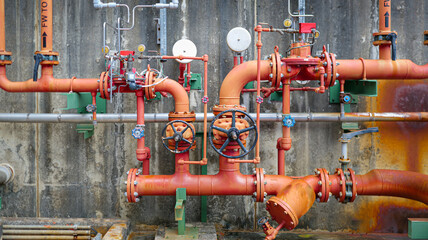 Red pipes and valves, which are components of a fire suppression or sprinkler system. red fire sprinkler pipes, industrial valve system, fire suppression network,