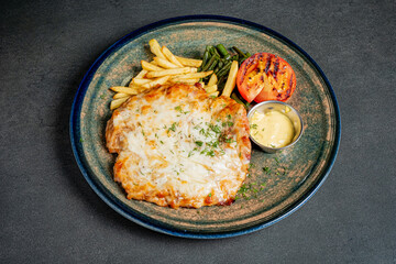Succulent grilled chicken topped with melted cheese, surrounded by vibrant veggies and fries