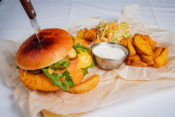 A delicious crispy chicken sandwich is served with golden potato wedges and creamy dip