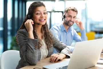 Customer service representatives engaged in professional work using headsets and laptops.