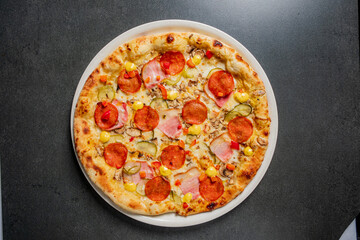 A delicious pizza features layers of pepperoni, ham, and fresh vegetables, tempting all who see it