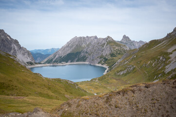 L&uuml;nersee - Panorama eines kristallklaren Bergsees in den Alpen mit Staumauer 