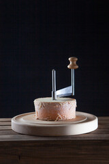 Traditional aged Tete des Moines cheese on wooden board. Special knife for slicing cheese "Girol". Black background.Copy space.