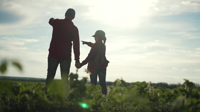 Farmer family in crop field at sunset. Father daughter bonding. Learning about crop agriculture. family exploring agriculture together. Father teaching daughter farming. Family experiencing crop field