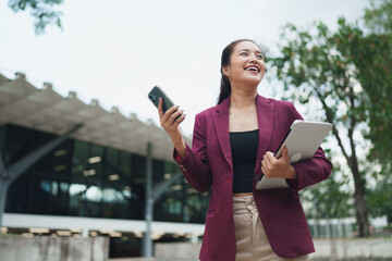 Young businesswoman smiling looking away holding phone and tablet