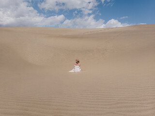 Woman in White Dress Sitting in Desert Landscape