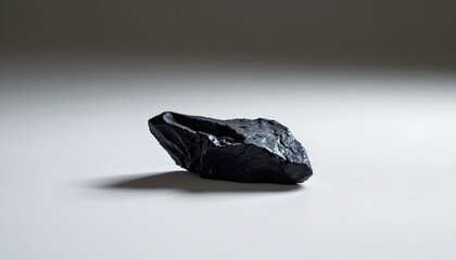 A solitary black rock, with the lower half of the rock obscured from view by an overlay of white vertical lines