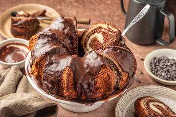Chocolate marble bundt cake or zebra cake with chocolate glaze sliced on brown table background