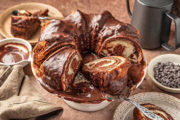 Chocolate marble bundt cake or zebra cake with chocolate glaze sliced on brown table background