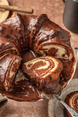 Chocolate marble bundt cake or zebra cake with chocolate glaze sliced on brown table background, close up