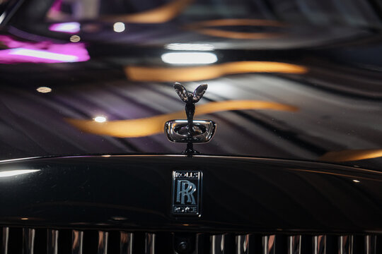 The Spirit of Ecstasy hood ornament and front grille of a Rolls-Royce automobile, showing the logo and branding. Rolls-Royce Spectre Black Badge.