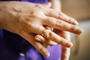 Hand wearing gold wedding ring with diamond on finger