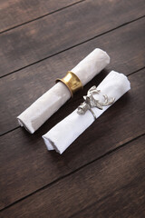 White napkin with a deer head serving ring. Napkin with brass ring. Festive table setting. Concept for New Year or Christmas. Wooden background. Top view with copy space. Flat lay.Vertical photo.