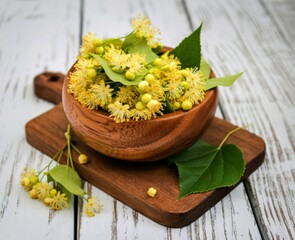 Freshly harvested linden flowers in a wooden bowl on a rustic table