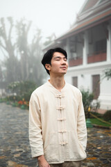 Obraz premium Serene portrait of a man in classic Asian attire enjoying quiet meditation outdoors in a foggy cultural temple setting
