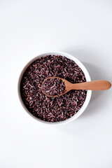 A bowl of black sticky rice grains isolated on white background