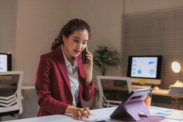 Businesswoman talking on cell phone while working late in modern office