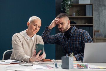 Coworkers finding a problem on smartphone at office