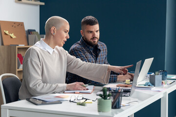 Business colleagues collaborating on project pointing at laptop screen