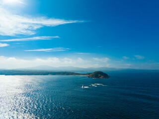 Serene coastal view featuring rocky islands under a bright blue sky during a peaceful afternoon by the ocean