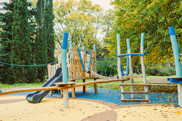 Children play and explore a colorful playground surrounded by lush trees on a bright autumn day