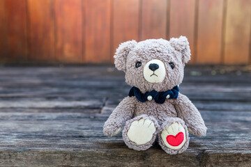 Teddy bear and red heart mark with space on wood background, valentine concept background idea