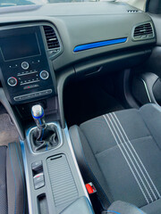 Interior view of a modern car showcasing detailed dashboard and gear shift during a sunny day drive in a suburban area