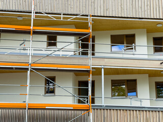 Construction workers enhance a modern building using scaffolding in an urban setting during a sunny day
