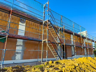 Construction project underway with scaffolding and clear blue sky brightening the scene in a bustling urban setting