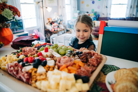 Young girl enjoying charcuterie board at home celebration