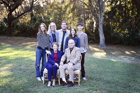 Three-generation family portrait with elders seated outdoors.
