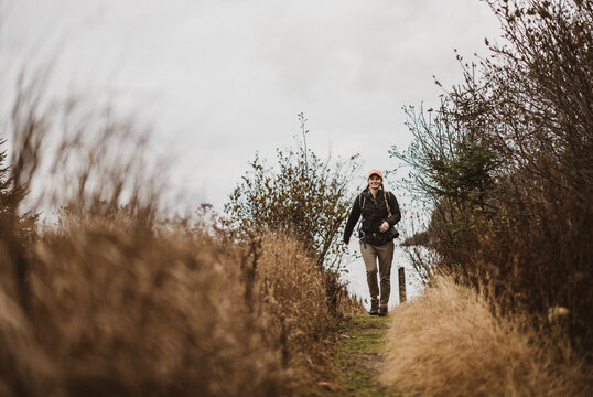 Female hiker walks through along trail through grass near Lubec, Maine