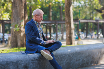 Obraz premium Mature man casually working on laptop in park