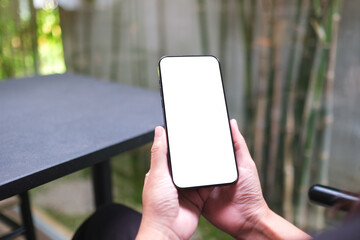 Mockup image of a woman holding and using mobile phone with blank desktop screen in cafe