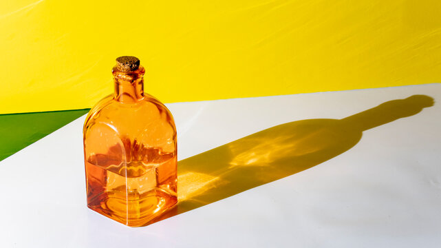 jar, square glass bottle of transparent brown color with yellow background and elongated shadows