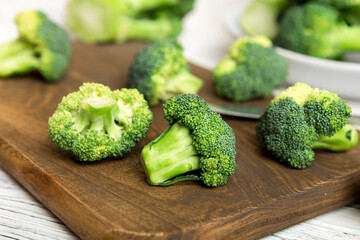 fresh green broccoli on wooden cutting board with knife. Broccoli cabbage leaves. light background. Flat lay