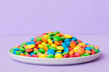 Multicolored candies in a bowl on a colored background. birthday and holiday concept. Top view with copy space