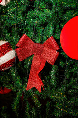 Festive Christmas tree decorated with red bows and ornaments under night sky with bright fireworks explosion above, holiday celebration outdoors, New Year atmosphere, winter festival mood