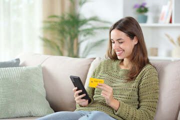 Happy woman in green buying online with card at home